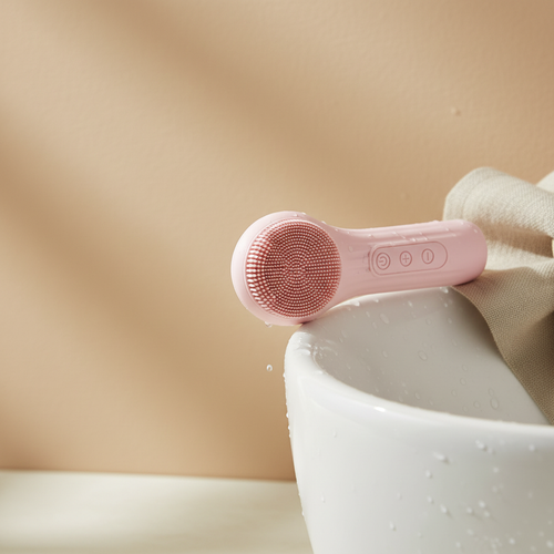 Femme utilisant la brosse nettoyante sonique Caresia sur le visage, mousse de nettoyant visible